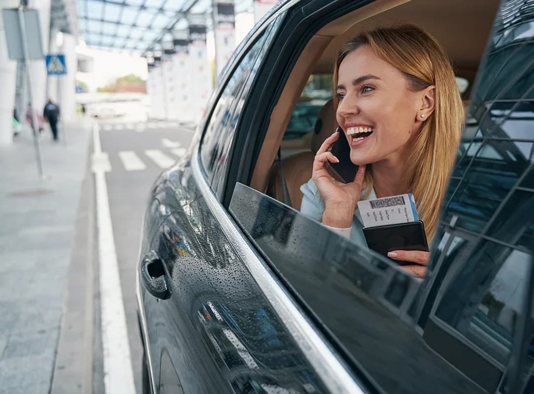 A traveler on the phone from a Bonvia vehicle at the terminal curb, boarding pass in hand.